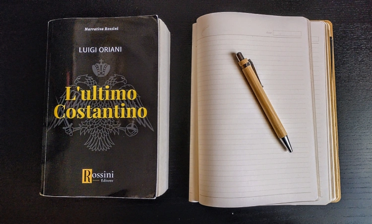 Foto del libro "L'ultimo Costantino" di Luigi Oriani accanto a un taccuino con sopra una penna in legno.
