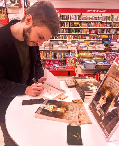 Foto di me in libreria mentre autografo una copia del mio romanzo "Come la neve a maggio".