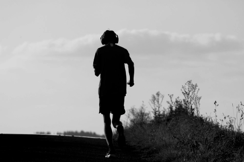 Foto in bianco e nero di un ragazzo che fa jogging all'aria aperta.