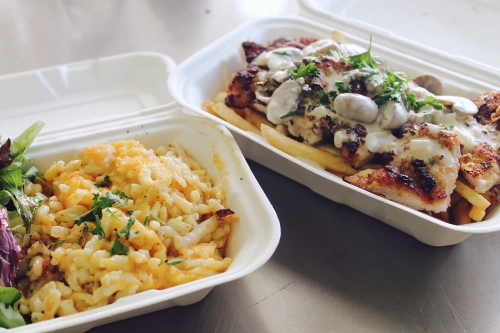 Foto di due vaschette con riso, pollo e insalata.