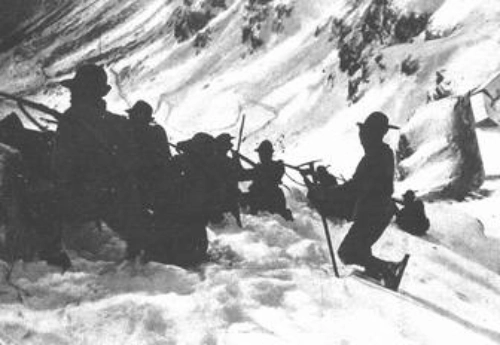 Foto di alpini in una trincea innevata di alta montagna.