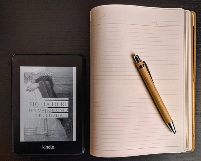 figlia di re copertina Foto del Kindle con la copertina del romanzo "Figlia di Re" poggiato su un tavolo nero, con accanto taccuino e penna